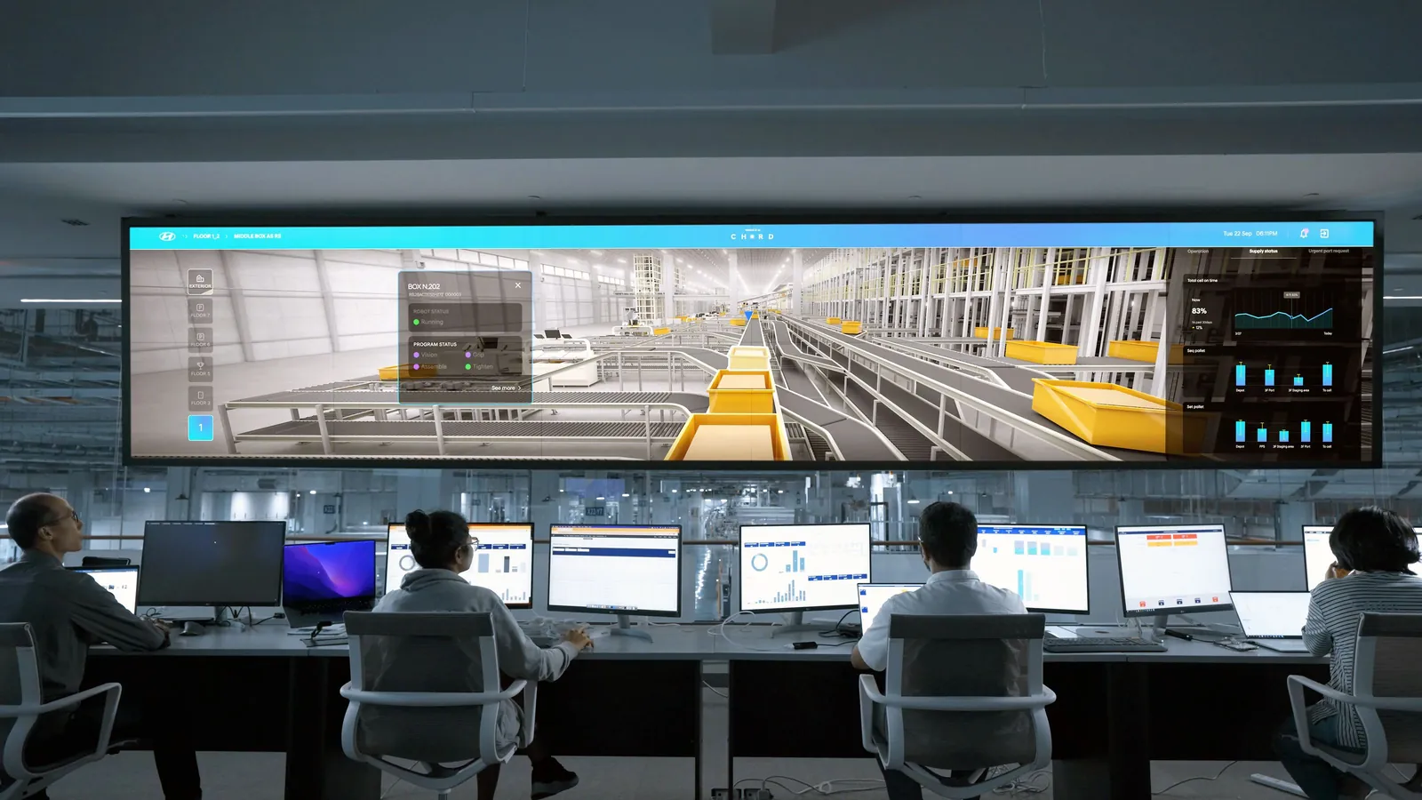 A team seated at computer workstations monitoring a large digital display in a control room